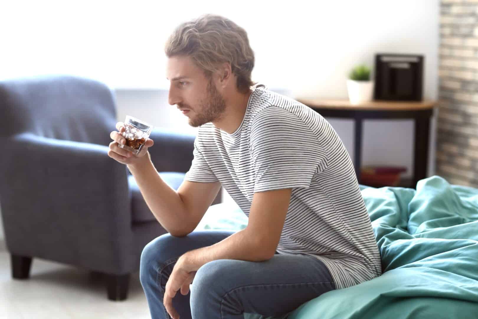 Person sitting and feeling the long-term effects of alcohol abuse